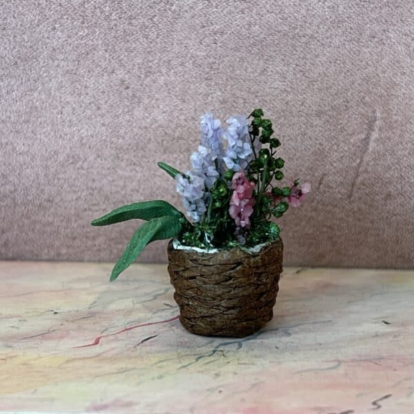 Flettet potteskjuler med blå og rosa blomster i miniature