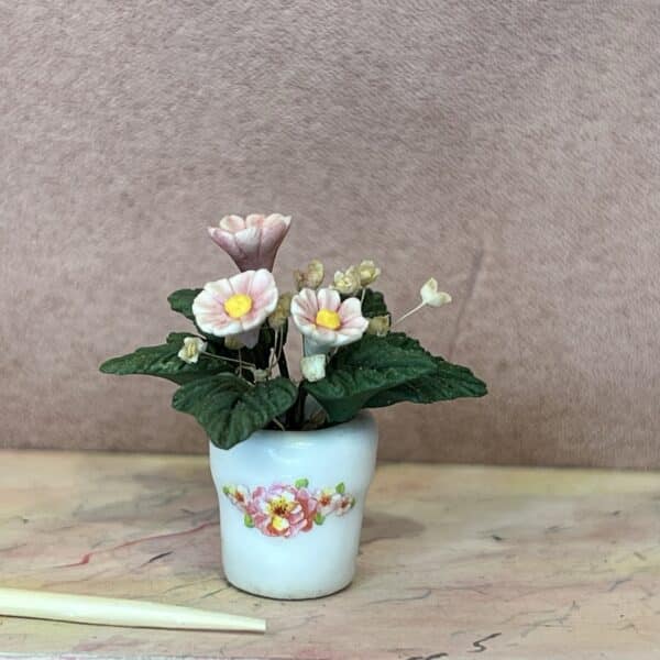 Sart rosa potteplante i sød hvid urtepotteskjuler